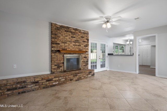 unfurnished living room featuring french doors, light tile patterned flooring, a brick fireplace, and ceiling fan with notable chandelier