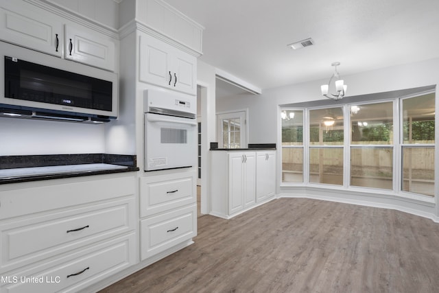 kitchen featuring oven, light hardwood / wood-style flooring, white cabinets, and an inviting chandelier