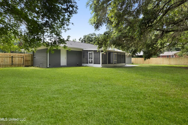 back of house featuring a lawn and a sunroom