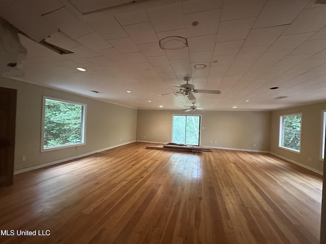 empty room featuring healthy amount of natural light, baseboards, and light wood finished floors