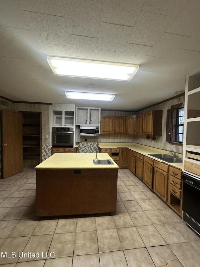 kitchen with stainless steel appliances, open shelves, a kitchen island with sink, and a sink