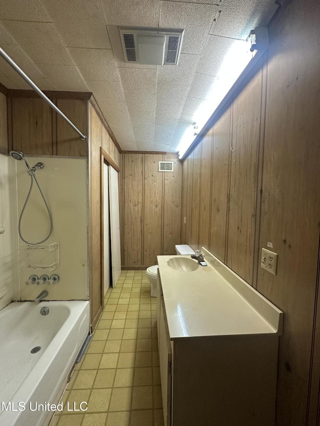 bathroom featuring wood walls, shower / bath combination, toilet, and vanity