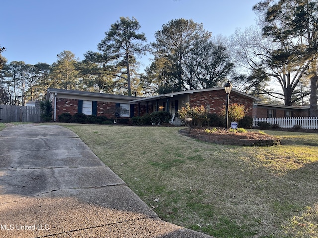 mid-century modern home with brick siding, a front lawn, and fence