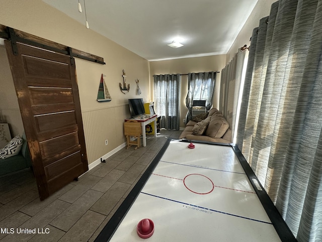 rec room with a wainscoted wall, a barn door, and wood tiled floor