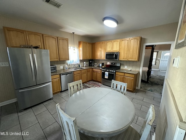 kitchen with visible vents, a sink, tasteful backsplash, stainless steel appliances, and wallpapered walls