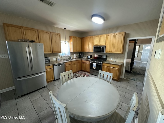 kitchen featuring wallpapered walls, decorative backsplash, visible vents, and stainless steel appliances