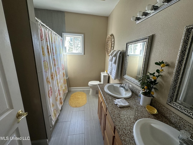 full bath with double vanity, toilet, baseboards, and a sink