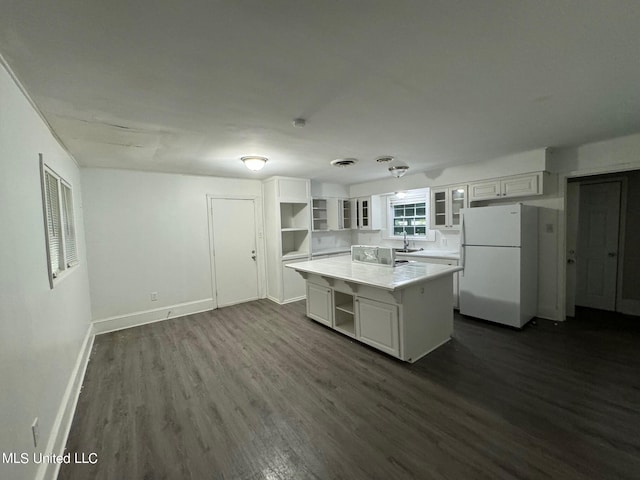 kitchen featuring a kitchen island, dark wood-type flooring, sink, white refrigerator, and white cabinets