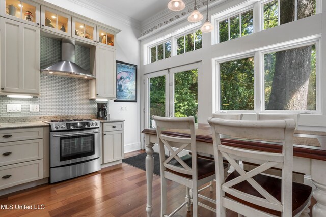 kitchen featuring dark hardwood / wood-style floors, wall chimney exhaust hood, stainless steel electric stove, crown molding, and pendant lighting