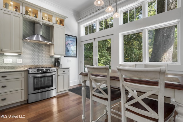kitchen with wall chimney range hood, dark wood-style flooring, crown molding, gas range, and tasteful backsplash