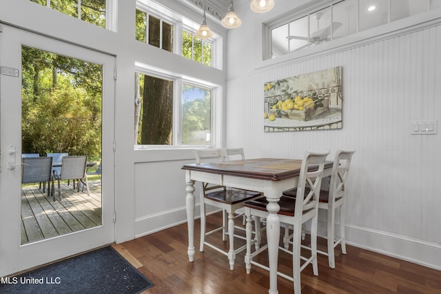 dining space with baseboards, a high ceiling, and wood finished floors