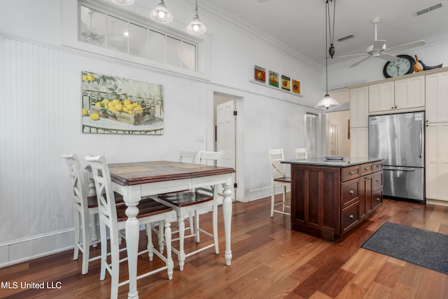 kitchen featuring ornamental molding, stainless steel fridge, a center island, and hanging light fixtures