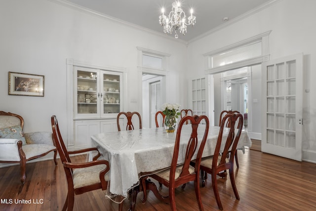 dining room with crown molding, a notable chandelier, dark wood-style floors, and french doors
