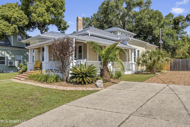 view of front facade featuring covered porch, a chimney, and a front yard