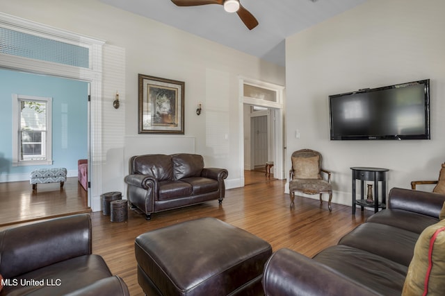 living room with baseboards, a ceiling fan, and wood finished floors