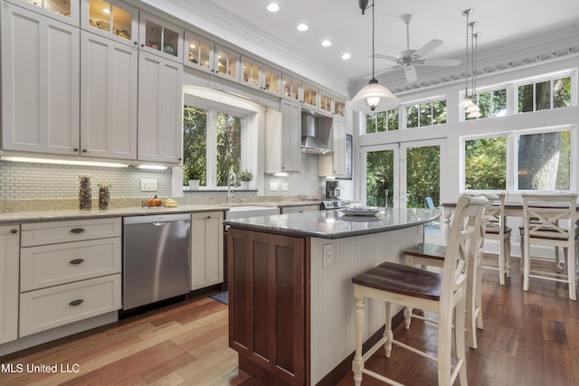 kitchen featuring ceiling fan, a kitchen island, tasteful backsplash, dishwasher, and a sink