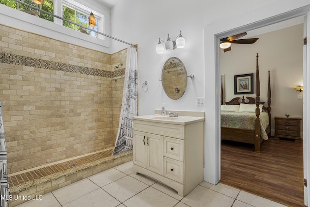 full bathroom featuring ceiling fan, tile patterned flooring, a tile shower, vanity, and ensuite bathroom