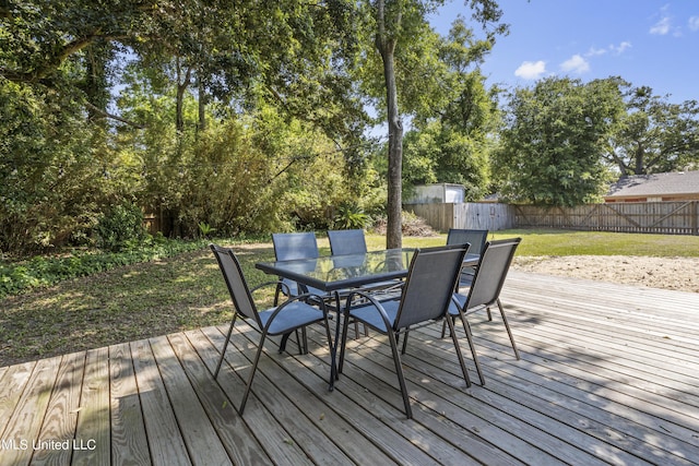 deck with a fenced backyard, outdoor dining area, and a lawn