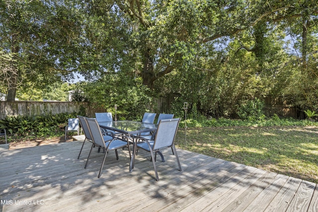 wooden deck featuring a fenced backyard, a yard, and outdoor dining space