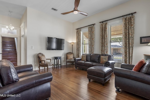 living area with visible vents, stairs, baseboards, hardwood / wood-style flooring, and ceiling fan with notable chandelier