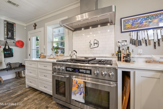 kitchen featuring wall chimney range hood, white cabinets, dark hardwood / wood-style flooring, range with two ovens, and crown molding