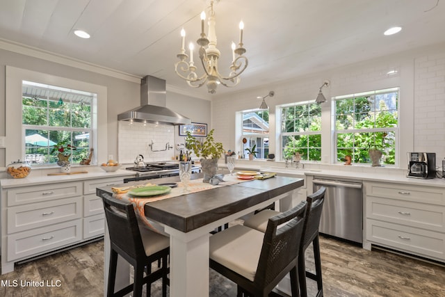 kitchen with wall chimney exhaust hood, dishwasher, white cabinets, and plenty of natural light