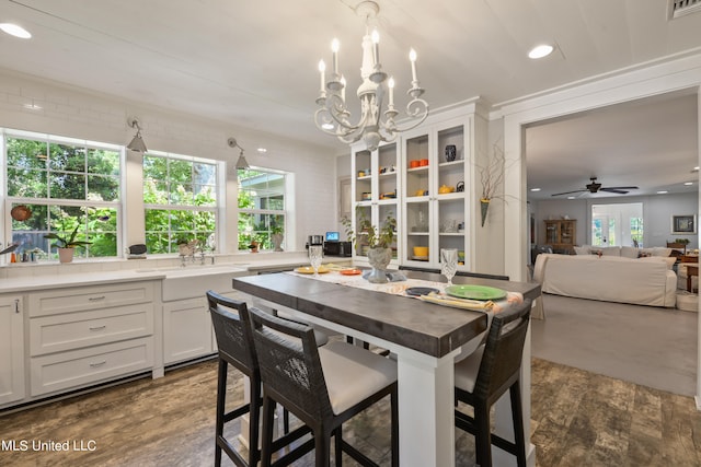 dining room featuring dark wood-type flooring, sink, and ceiling fan with notable chandelier