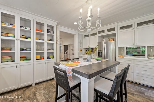 kitchen with a kitchen bar, a center island, stainless steel appliances, white cabinets, and dark wood-type flooring