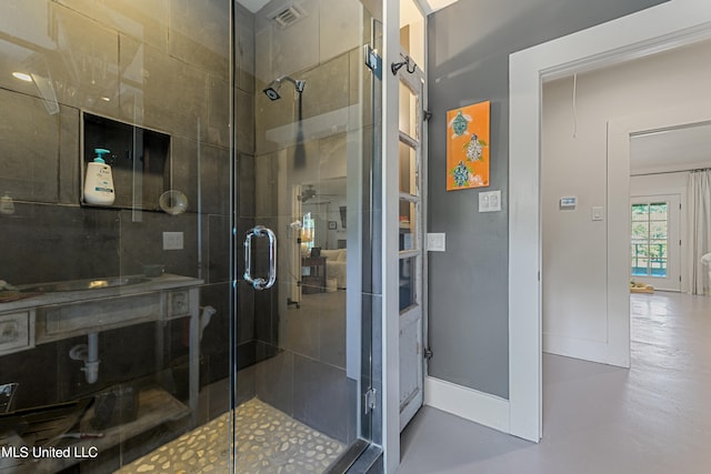 bathroom with a shower with shower door and concrete floors