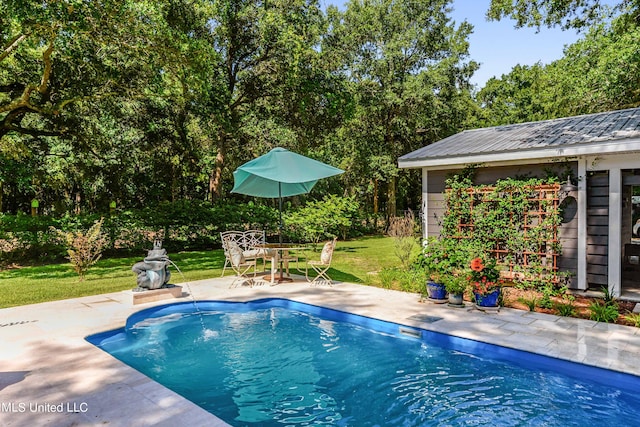 view of swimming pool featuring a patio, an outdoor structure, and a lawn