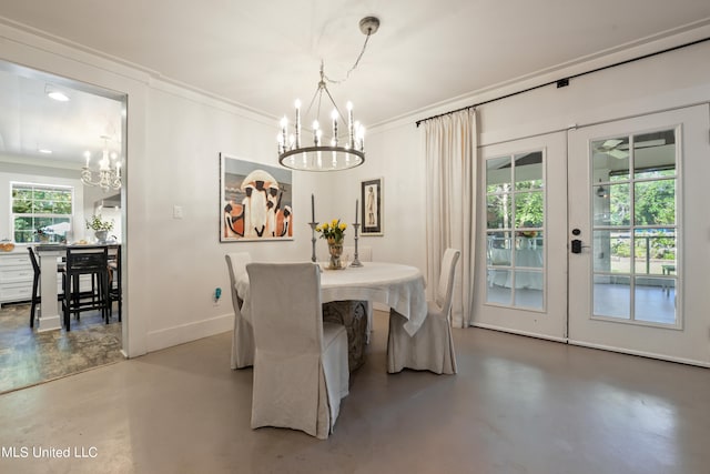 dining area with french doors, concrete floors, a notable chandelier, and ornamental molding