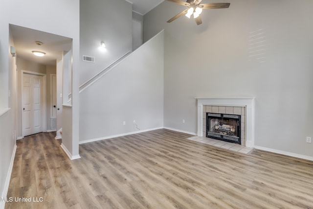 20 Oakmont Pl, Long Beach, MS 39560 - unfurnished living room featuring a high ceiling, a ceiling fan, wood finished floors, a tile fireplace, and stairway
