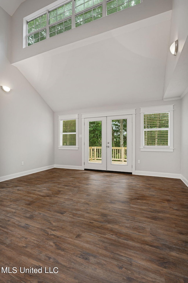 unfurnished living room featuring dark wood-type flooring, high vaulted ceiling, a healthy amount of sunlight, and french doors