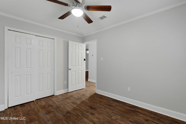 unfurnished bedroom with dark wood-type flooring, crown molding, a closet, and ceiling fan