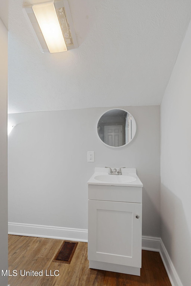 bathroom with vanity, lofted ceiling, and hardwood / wood-style floors