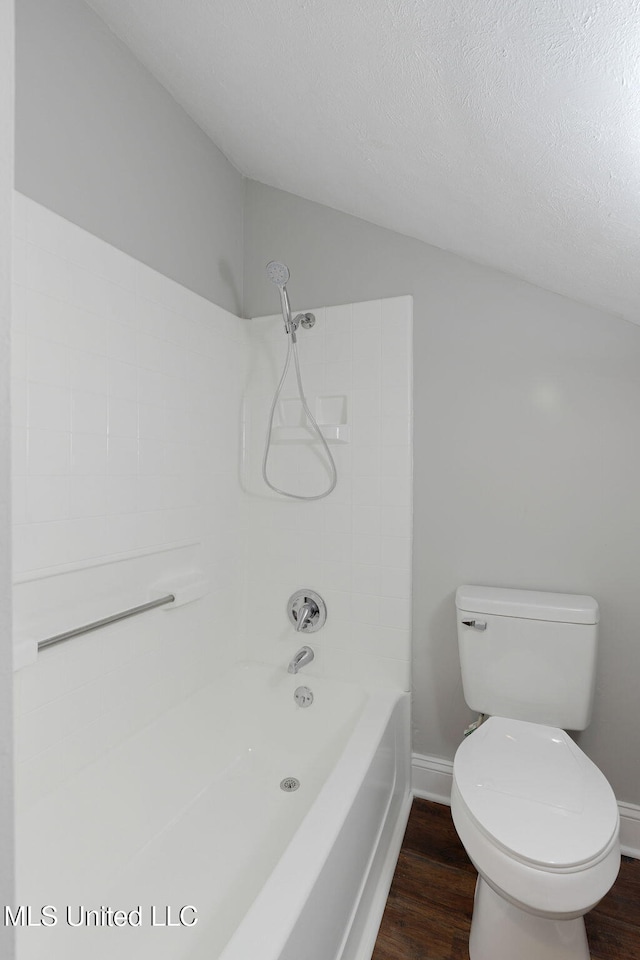 bathroom with a textured ceiling, washtub / shower combination, wood-type flooring, and toilet