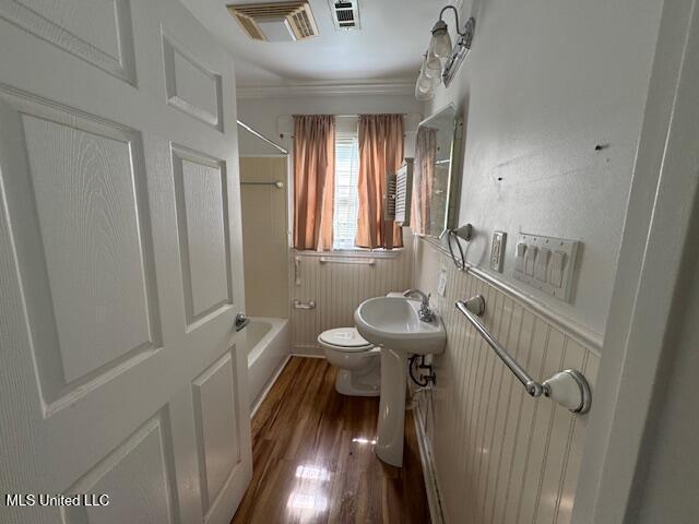 165 Canal St, Gulfport, MS 39507 - bathroom with toilet, wood finished floors, wainscoting, bathing tub / shower combination, and a sink