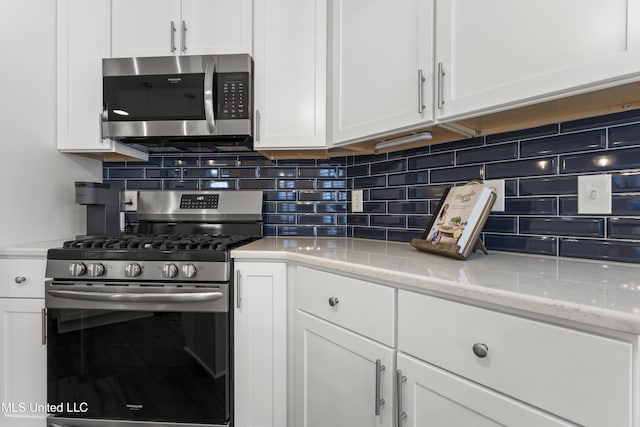 2252 Beach Dr Unit 606, Gulfport, MS 39507 - kitchen featuring stainless steel appliances, white cabinetry, decorative backsplash, and light stone countertops