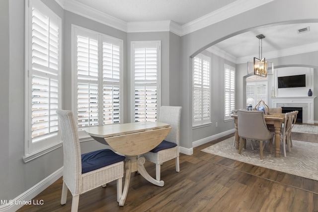 2252 Beach Dr Unit 606, Gulfport, MS 39507 - dining room with wood finished floors, a chandelier, arched walkways, crown molding, and a fireplace