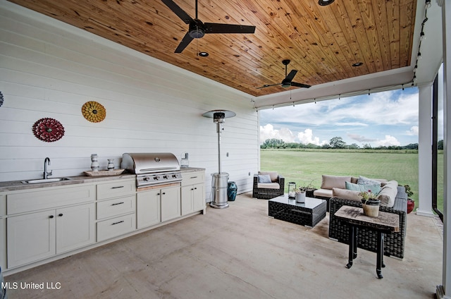 view of patio featuring a grill, exterior kitchen, a rural view, sink, and ceiling fan