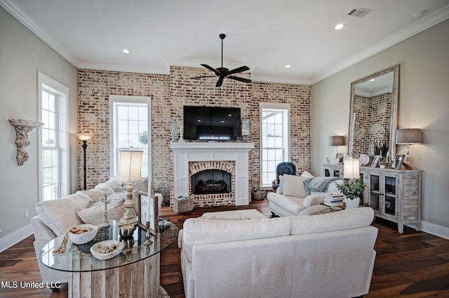 living room featuring dark wood-type flooring, a brick fireplace, crown molding, and ceiling fan