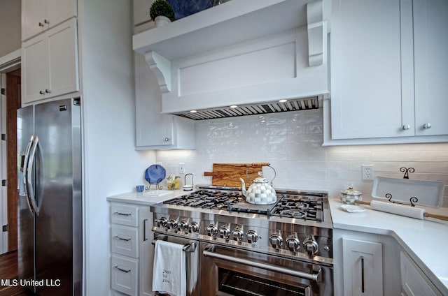 kitchen with appliances with stainless steel finishes, white cabinets, custom range hood, and backsplash