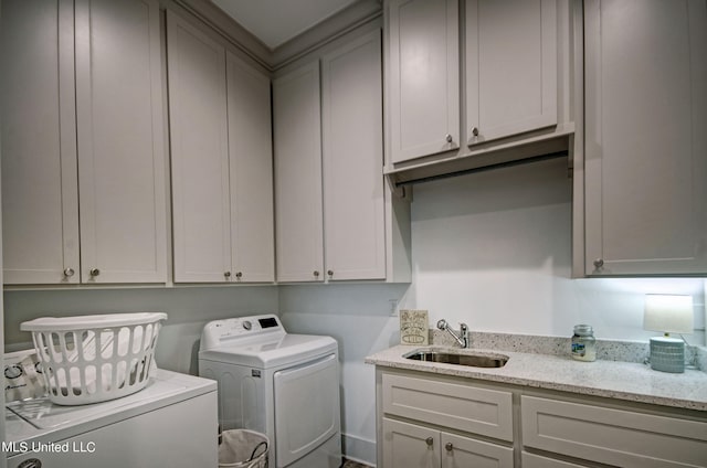 clothes washing area with cabinets, sink, and washer and clothes dryer