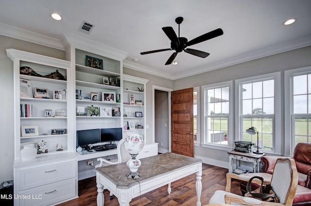 home office with crown molding, built in desk, dark wood-type flooring, and ceiling fan