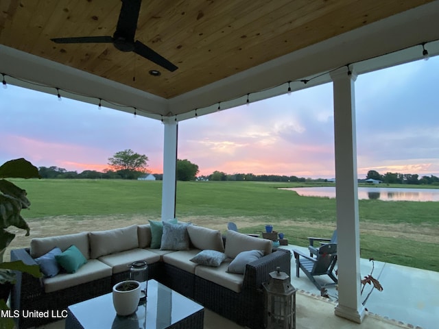 patio terrace at dusk with outdoor lounge area, a yard, a water view, and ceiling fan