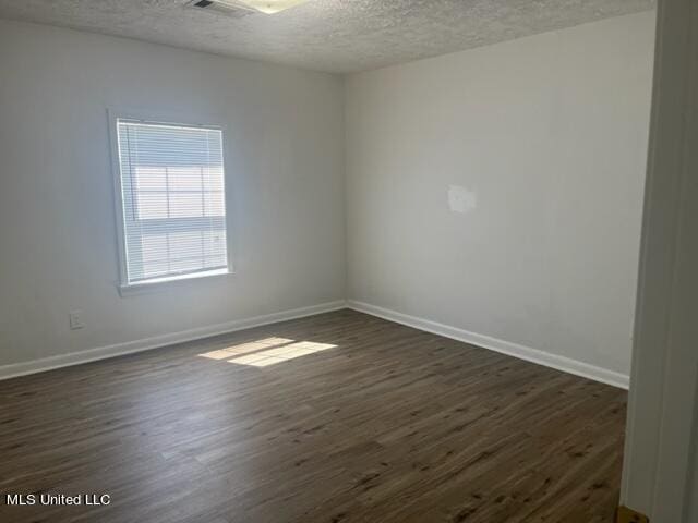 empty room with a textured ceiling and dark hardwood / wood-style floors