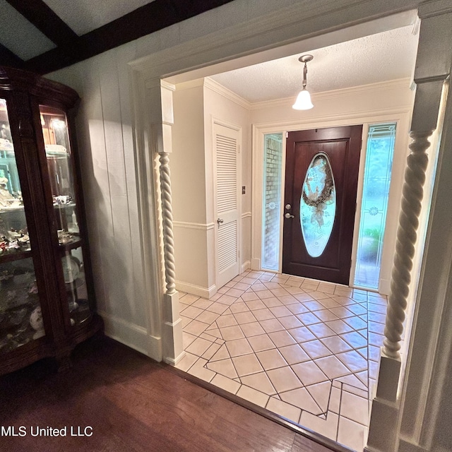 tiled foyer featuring ornamental molding and a textured ceiling