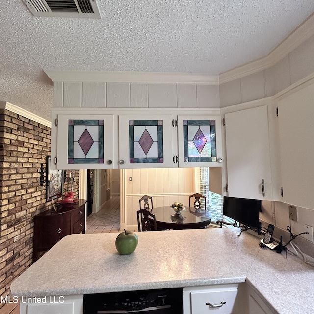 kitchen featuring white cabinets, a textured ceiling, ornamental molding, light parquet floors, and brick wall