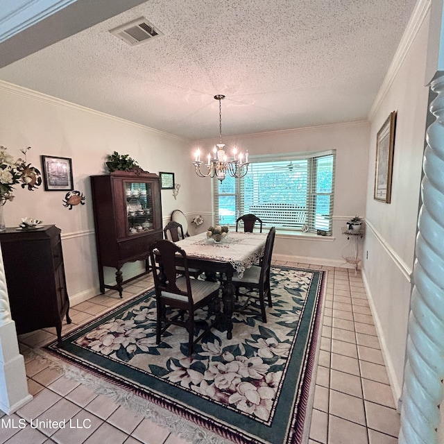 tiled dining area featuring crown molding, a textured ceiling, and an inviting chandelier