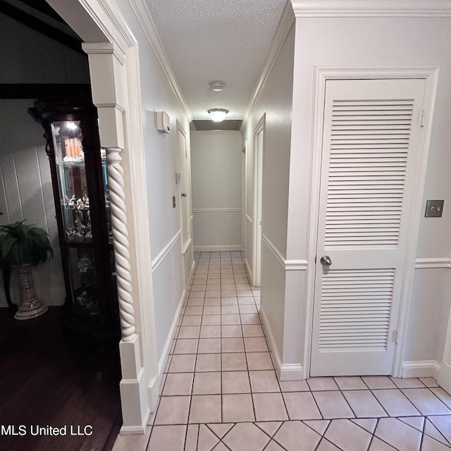 hall featuring ornamental molding, a textured ceiling, and light tile patterned floors